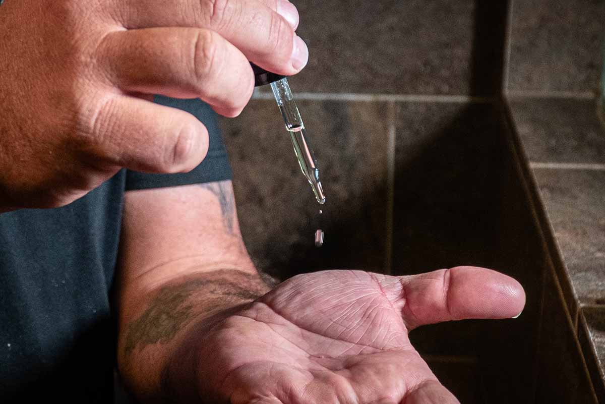 beard and body oil falling from a dropper into the palm of a hand