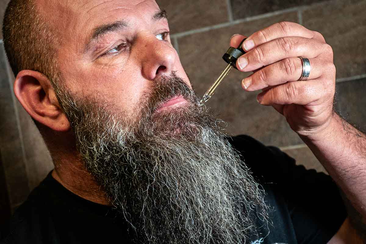beard and body oil falling from dropper into a beard