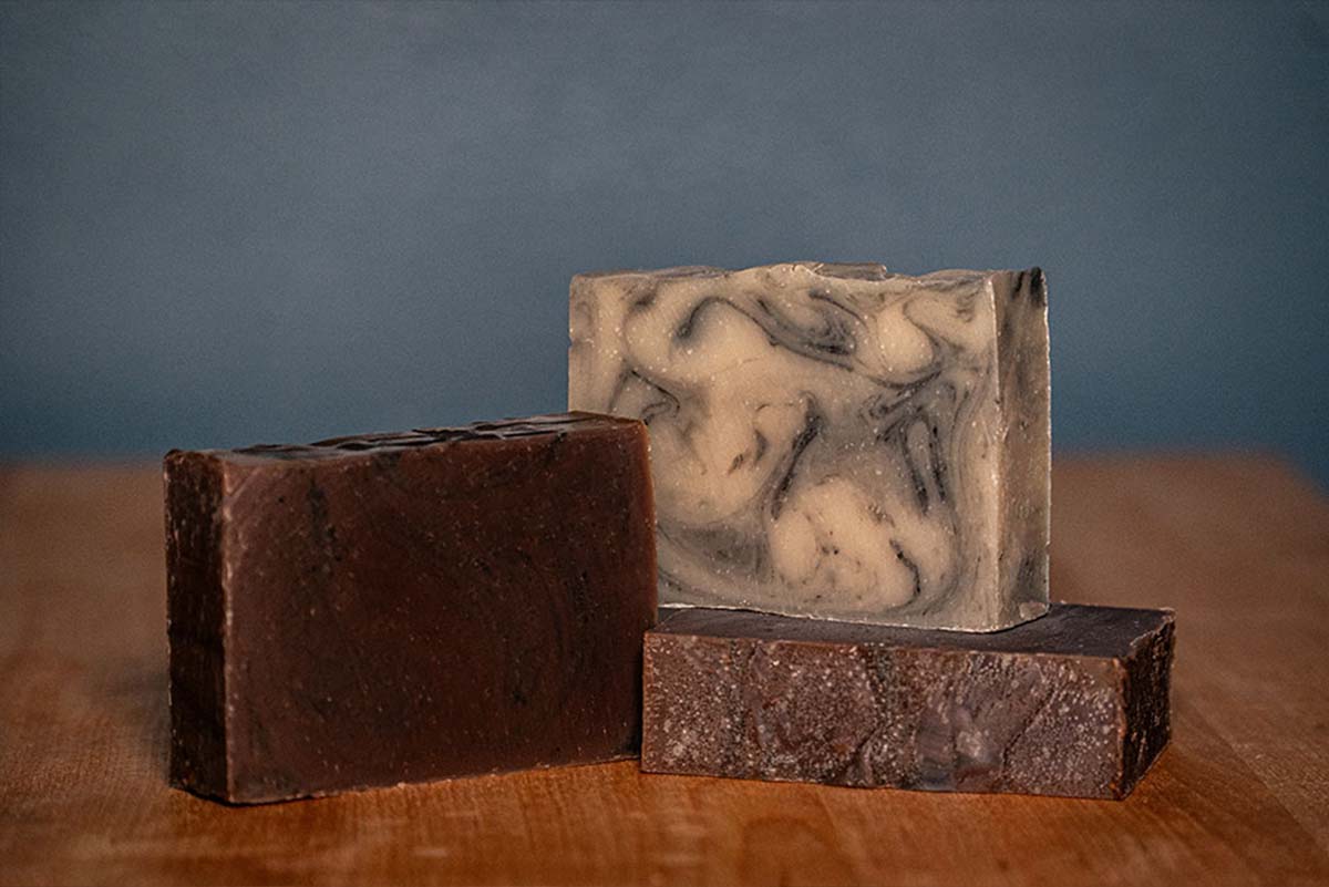 cold processed soaps stacked on wooden base with blue backdrop