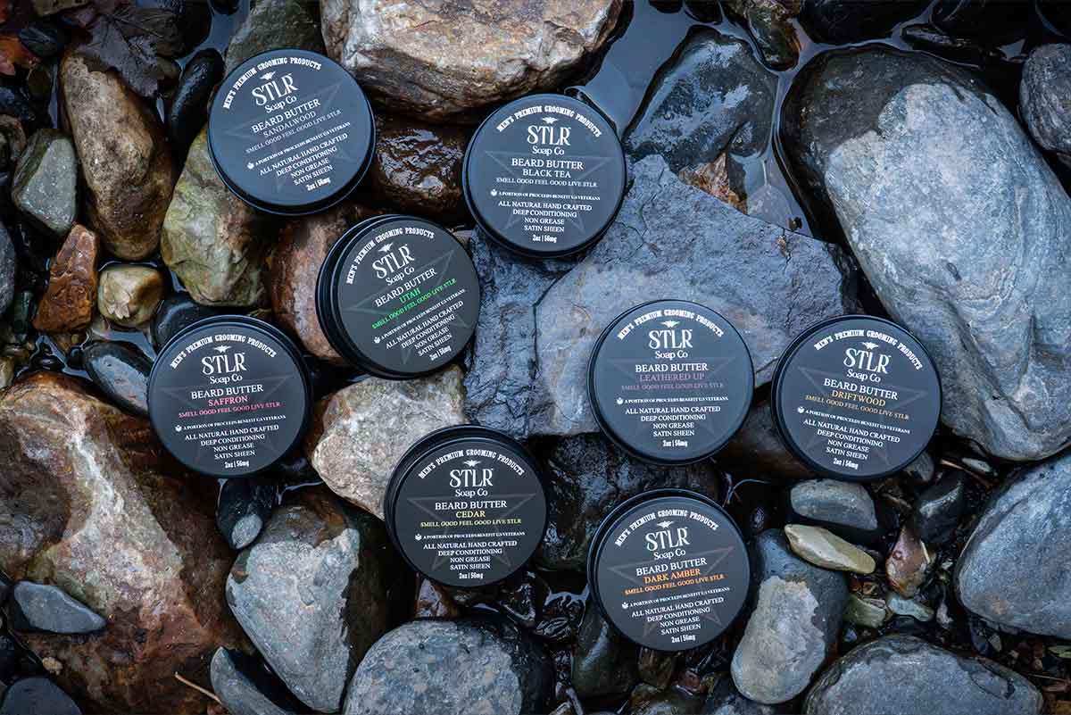 A collection of beard butter in a natural environment with rocks and water