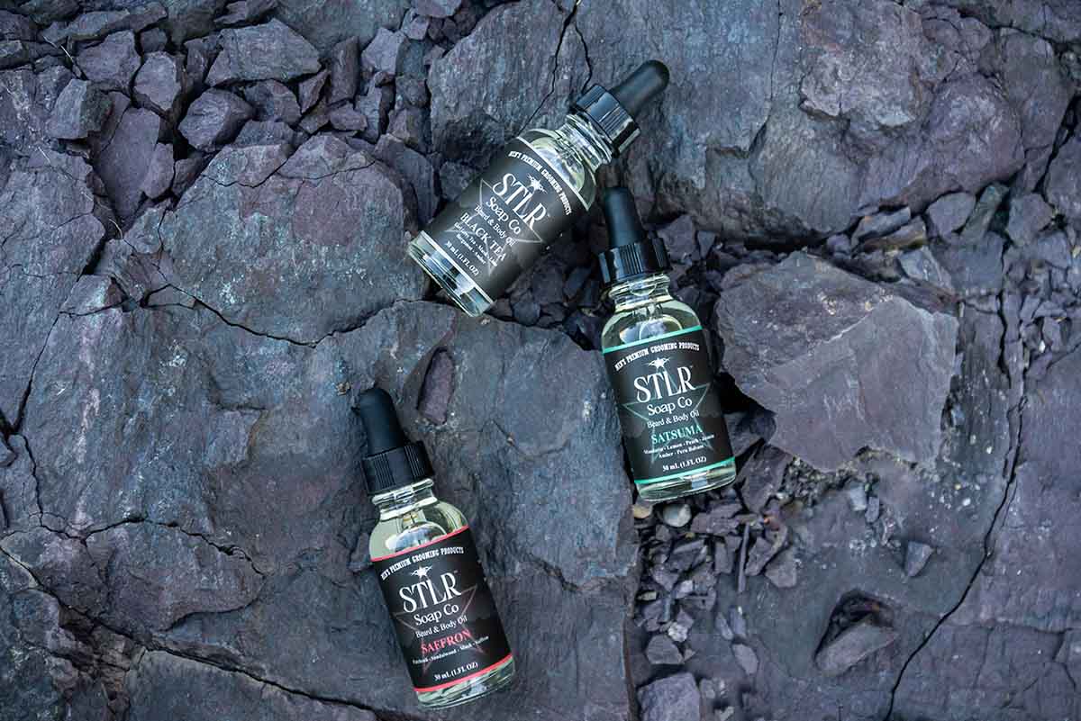 three beard and body oils on a natural rocky backdrop